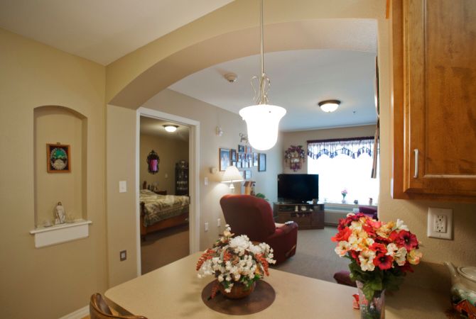 A cozy living room with comfortable seating, a television, and decorative flowers.