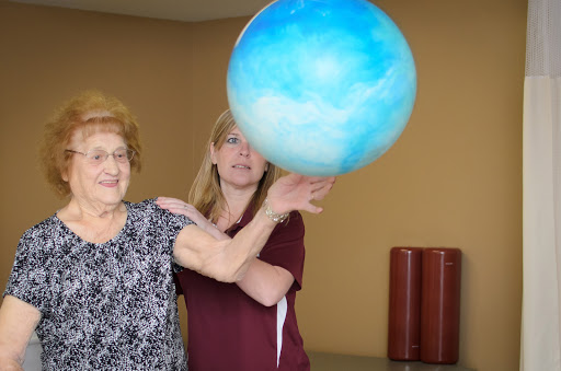 Two women enjoy a playful moment while handling a globe indoors.