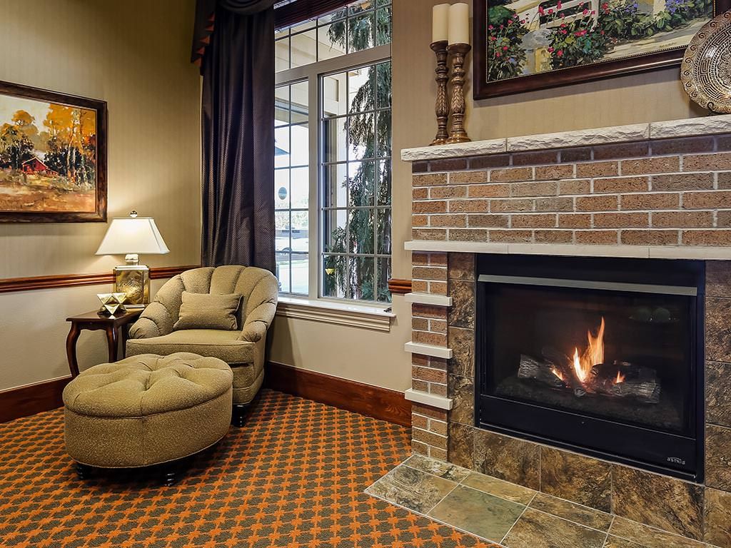 A cozy living room featuring a brick fireplace, comfortable armchair, and warm lighting.