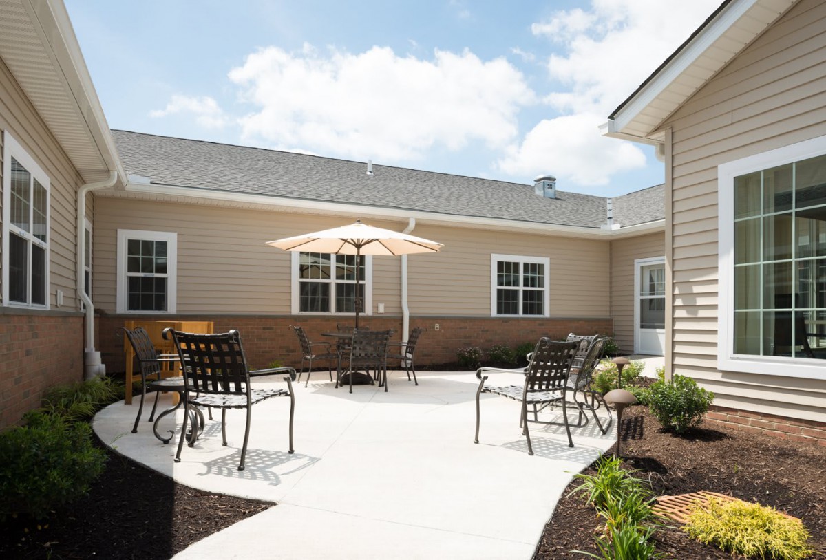 A sunny outdoor patio area with a table, chairs, and a sun umbrella.