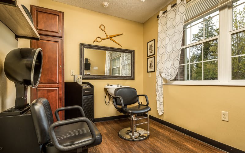 A cozy hair salon with stylish decor, featuring a chair and sink under a large mirror.
