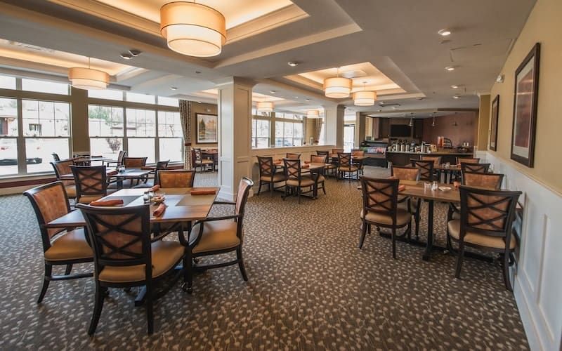 An elegantly designed restaurant dining area with neatly arranged tables and chairs, featuring large windows and stylish lighting.