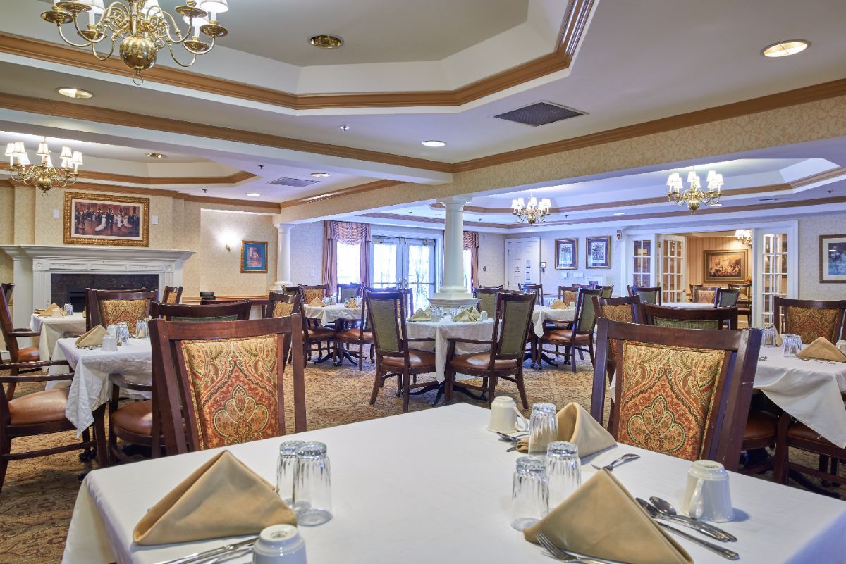 An elegant dining area with neatly arranged tables and chairs, featuring folded napkins and place settings.
