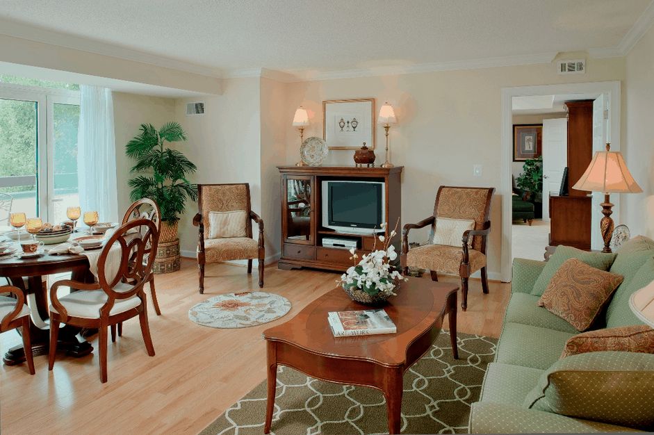 A traditionally styled living room featuring wooden furniture, a sofa, chairs, a coffee table, and a television.