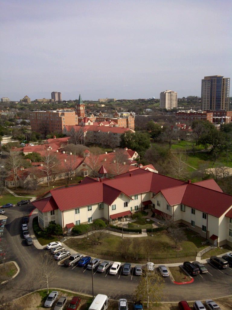 Aerial view of a neighborhood with red-roofed buildings and surrounding urban landscape.