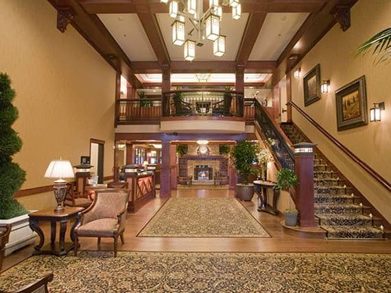 A spacious hotel lobby with elegant wooden accents, a grand staircase, and comfortable seating areas.