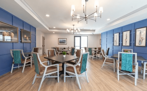 A modern dining area with stylish chairs and tables, featuring blue accents and a chandelier.