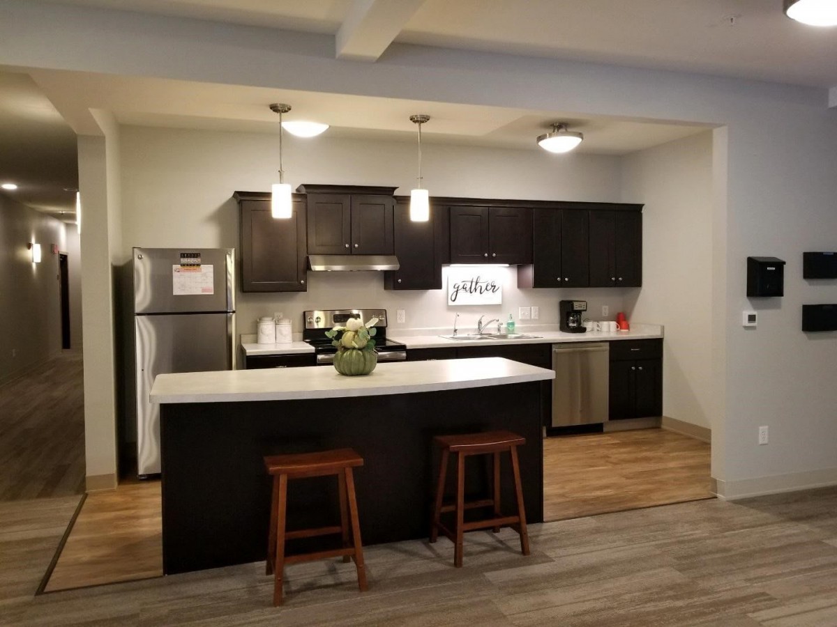 A modern kitchen with dark cabinets, a central island, and stylish bar stools.