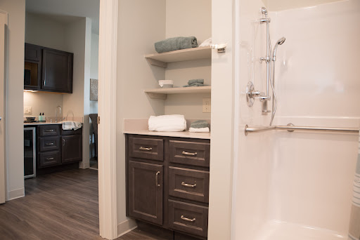 A stylish and modern bathroom featuring sleek cabinets, open shelves, and a clean shower area.