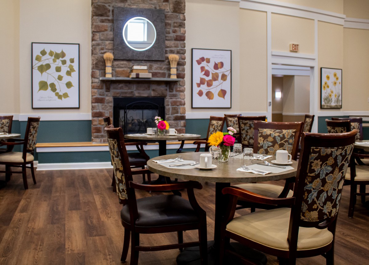 A cozy dining area with a beautifully set table and a fireplace surrounded by artwork.