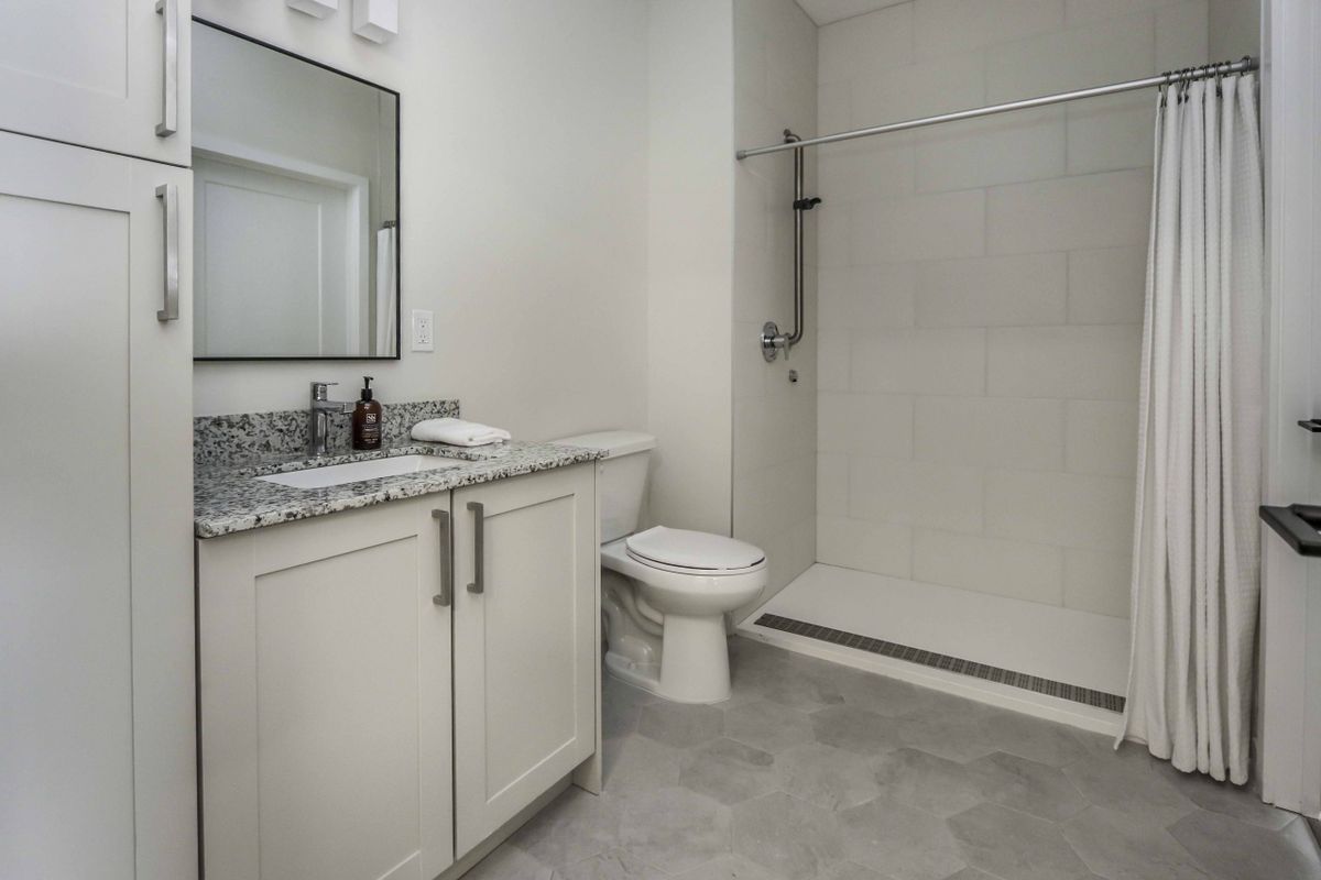 Modern bathroom with a granite countertop and walk-in shower.