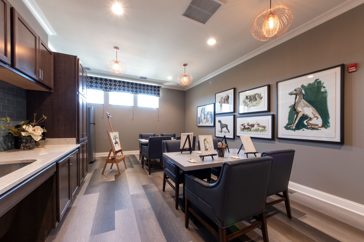 A stylish art studio with multiple workstations and paintings displayed on the wall.