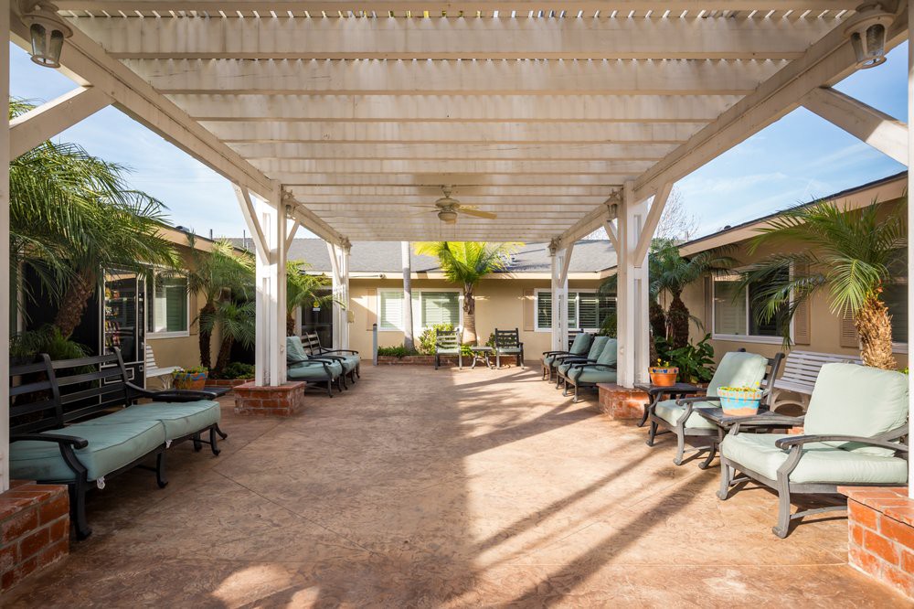 A spacious courtyard with a pergola, featuring outdoor seating and tropical plants.