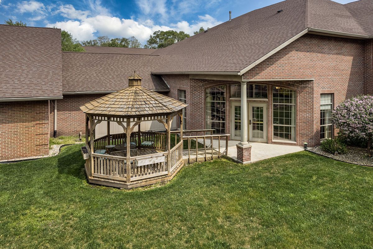 A backyard featuring a wooden gazebo and patio attached to a brick house.