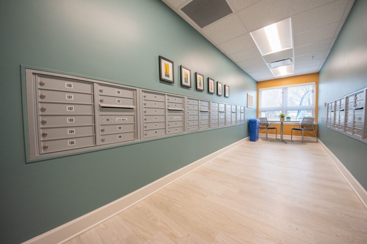 A modern office hallway with a row of mailboxes and framed artwork on the wall.