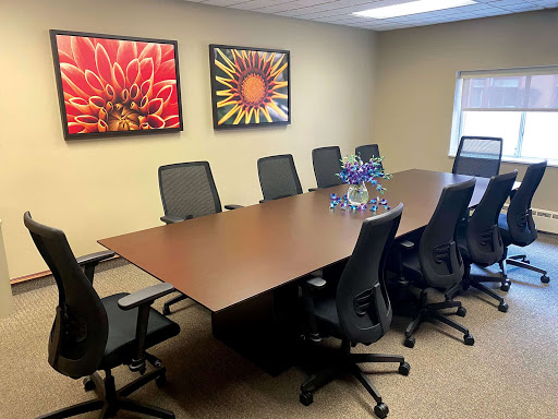 A modern conference room featuring a large wooden table surrounded by ergonomic chairs, complemented by vibrant floral artwork on the walls.