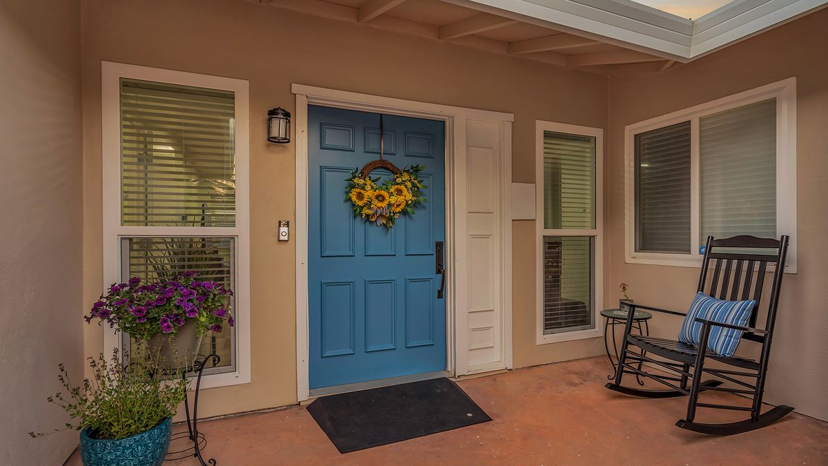 A welcoming blue front door adorned with a floral wreath, situated on a cozy porch.