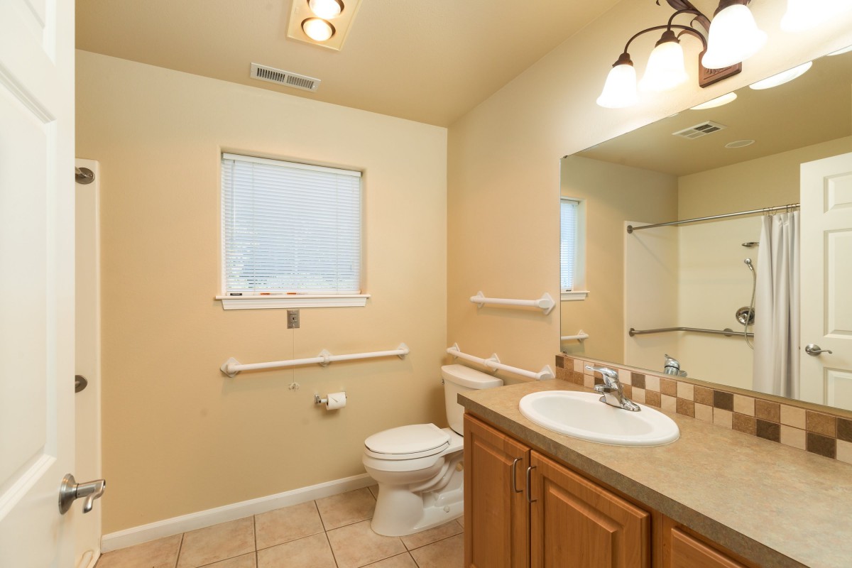A clean and well-lit bathroom with a sink, toilet, and mirror.