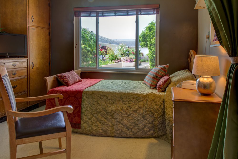 A cozy bedroom with a large window offering a scenic view of the outdoors, complete with comfortable furnishings and warm decor.