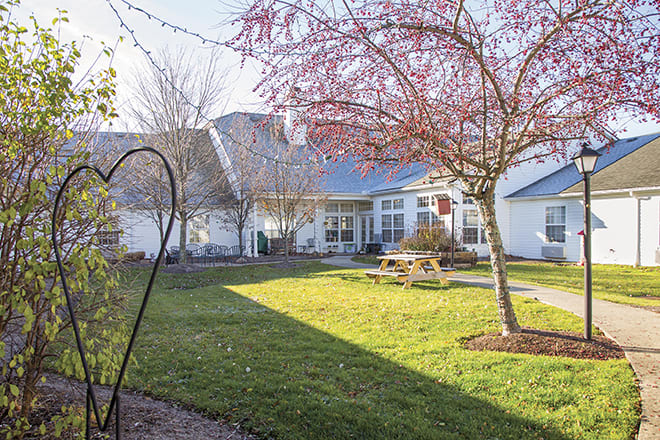 A well-maintained backyard with a lush lawn, trees, and a picnic table.