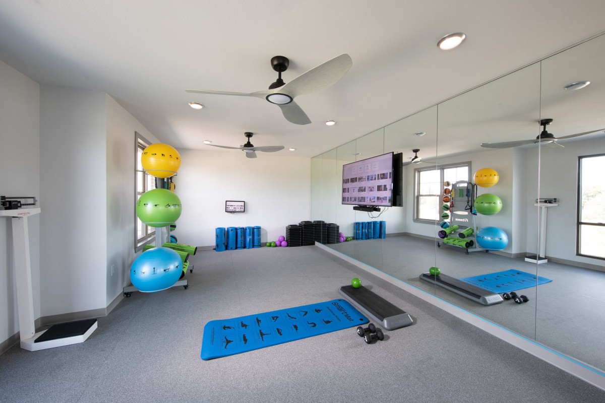 A bright and spacious home gym with exercise equipment and mirrored walls.