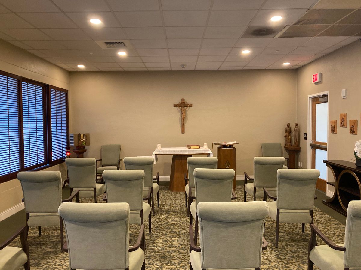 A small chapel with arranged seating facing a cross and altar.