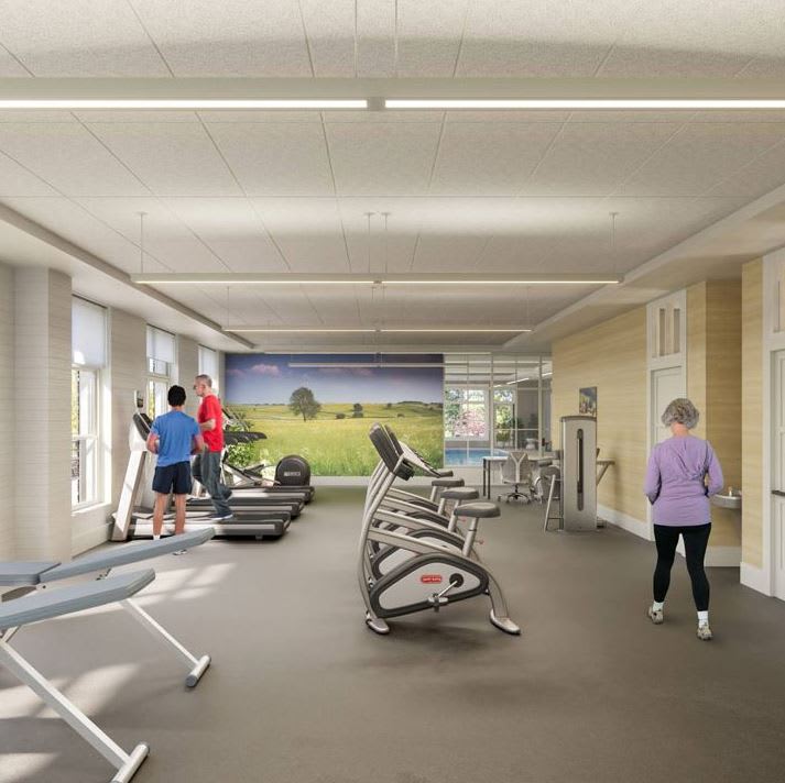 A spacious gym with fitness equipment and people exercising.