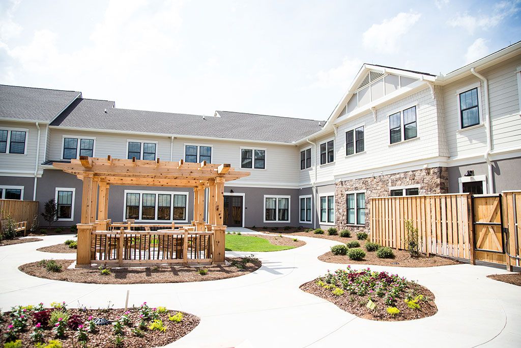 A spacious residential courtyard with well-maintained gardens and a wooden pergola.