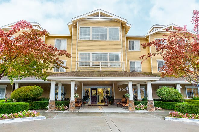 A multi-story residential building with a welcoming entrance surrounded by trees.
