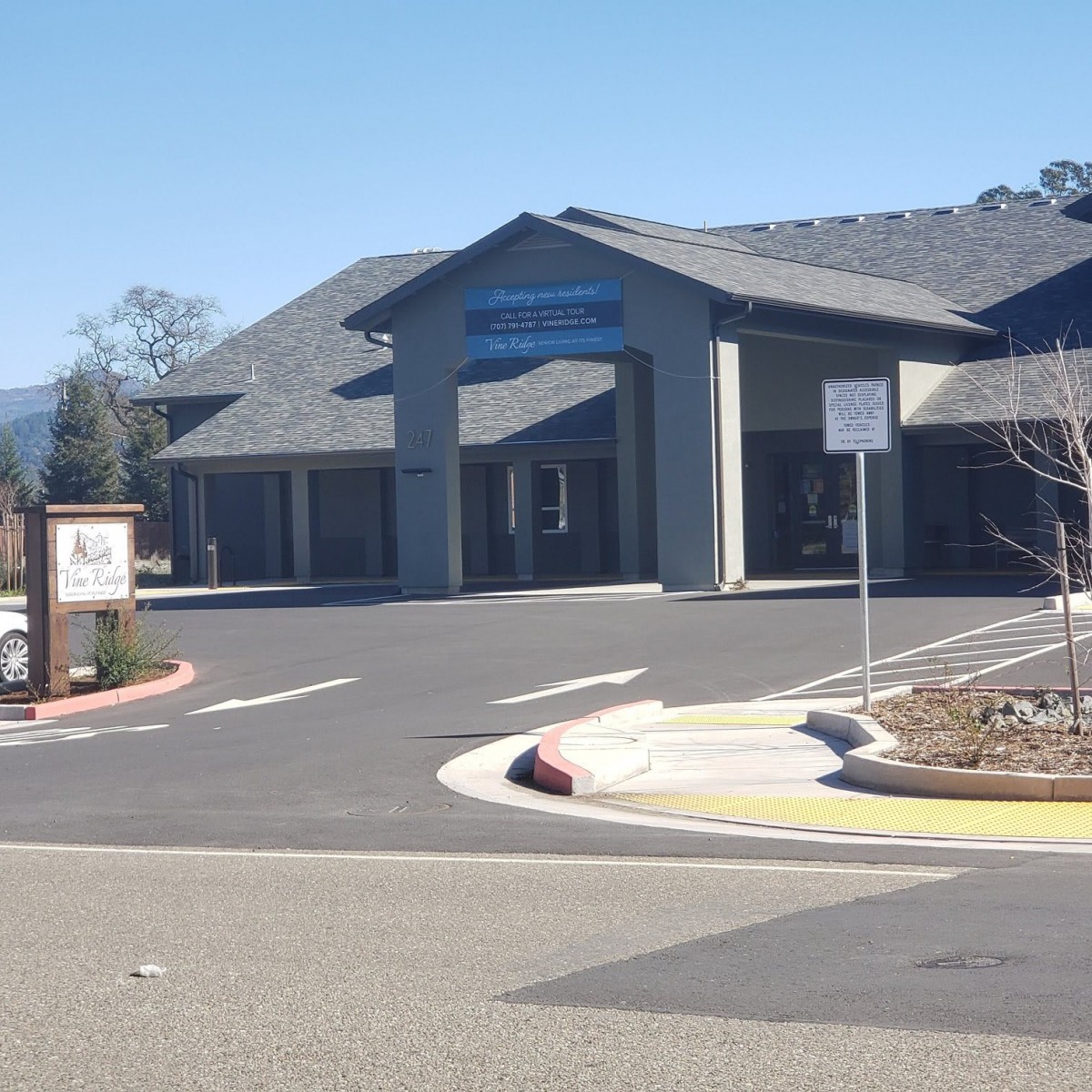A building with a parking lot in front, featuring signage and clear skies.