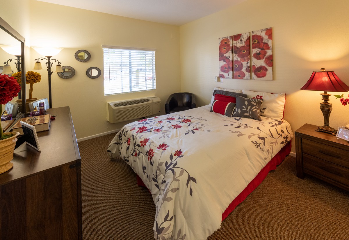 A cozy bedroom with floral bedding and decorative wall art.