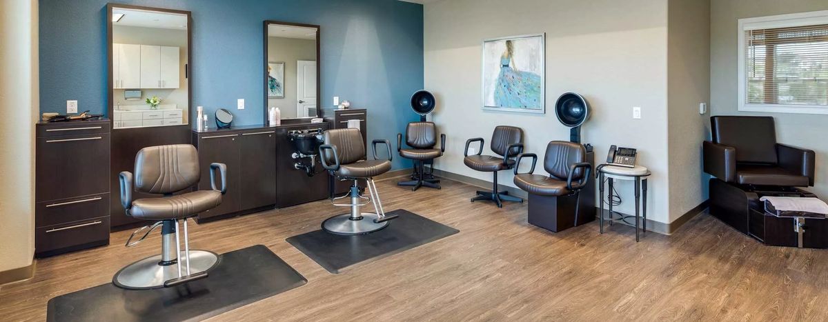 Interior of a modern hair salon with styling and dryer chairs.