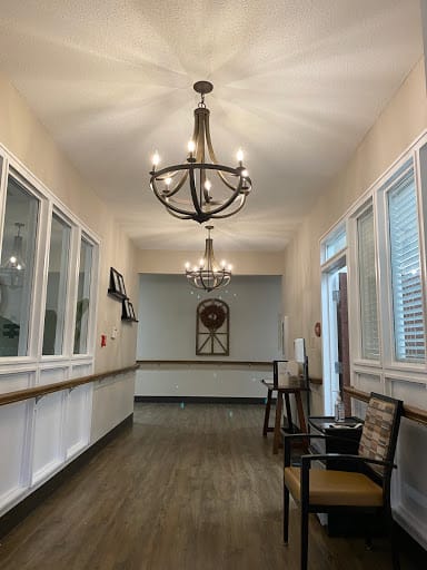 A well-lit hallway with chandeliers and comfortable seating.