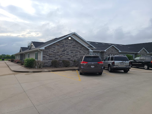 An exterior view of a building with parked cars in a cloudy setting.