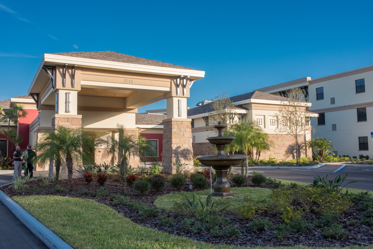 A modern building surrounded by landscaped gardens and a central fountain.