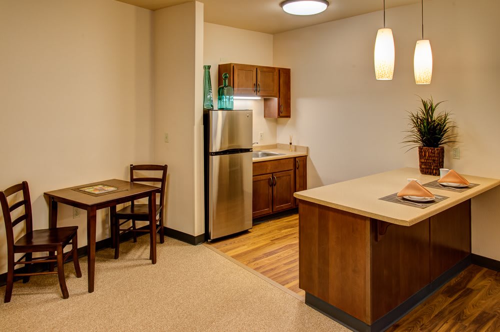 A modern apartment kitchen with an open layout featuring stainless steel appliances and wood cabinetry.