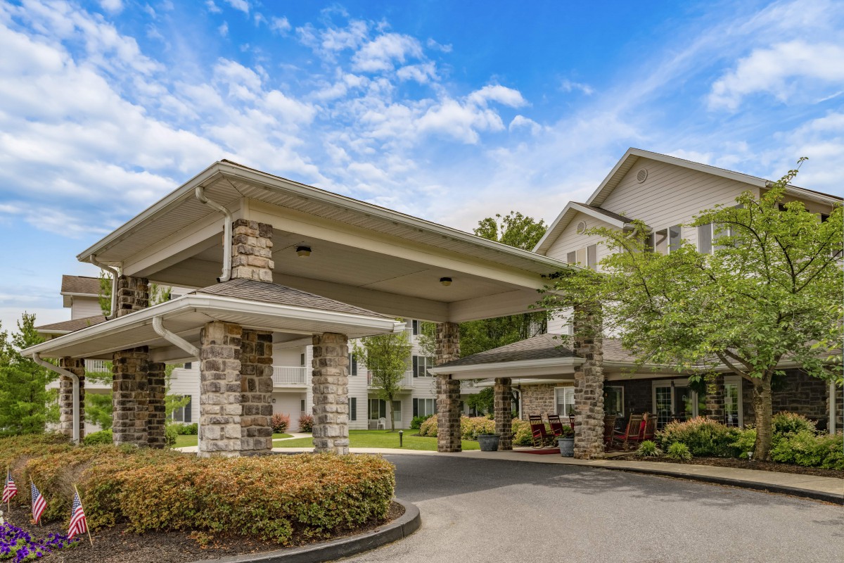 A view of a building entrance with stone pillars and a driveway.