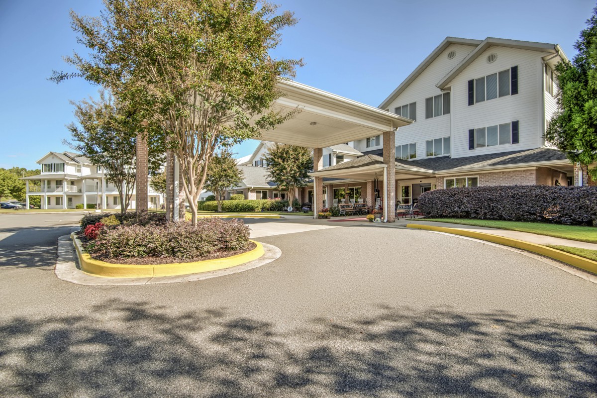 A welcoming entrance to a large building with well-maintained landscaping and a clear blue sky.