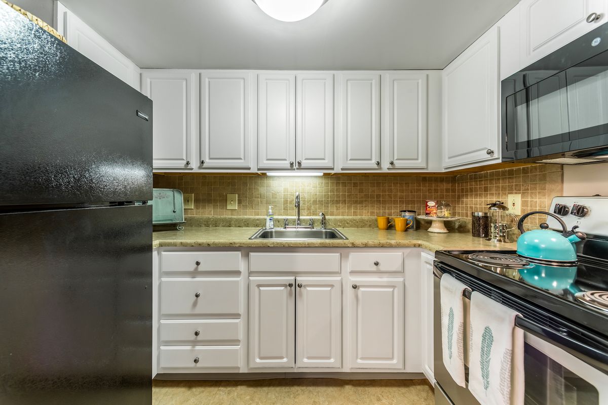 A modern kitchen with white cabinets and stainless steel appliances.