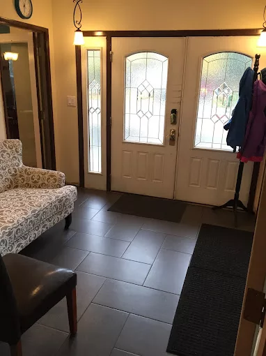 A tidy entryway with a patterned chair, coat rack, and double doors with frosted glass panels.