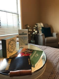 A cozy reading nook with a collection of books on a table near a comfortable chair.