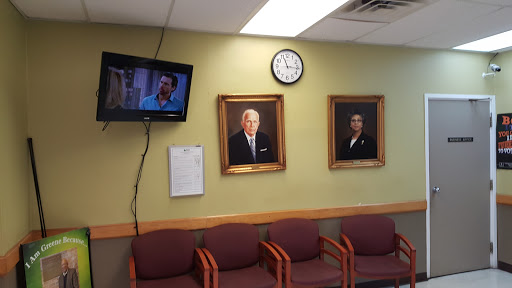 A waiting room featuring portraits on the wall, a television, and seating for visitors.