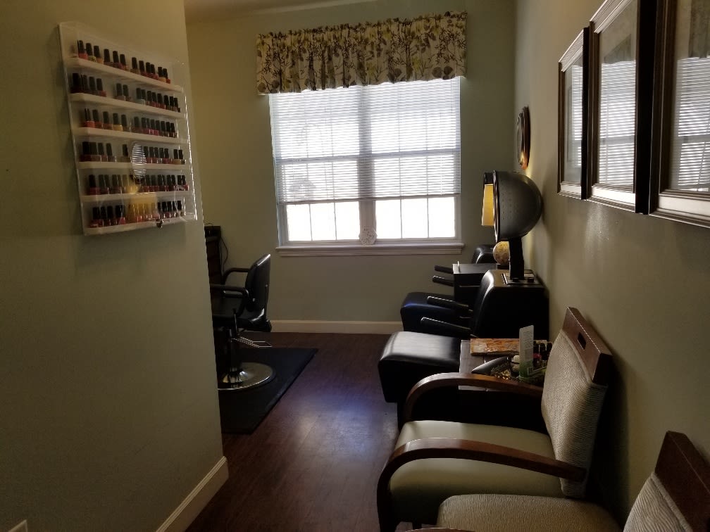 A cozy salon waiting area with chairs and a nail polish display.