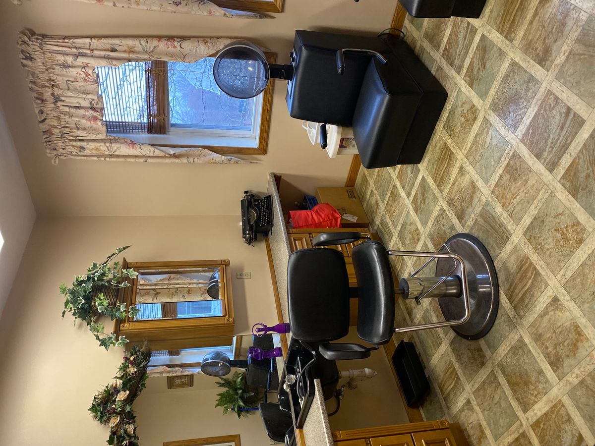 A cozy salon interior with a styling chair and hairdressing equipment.