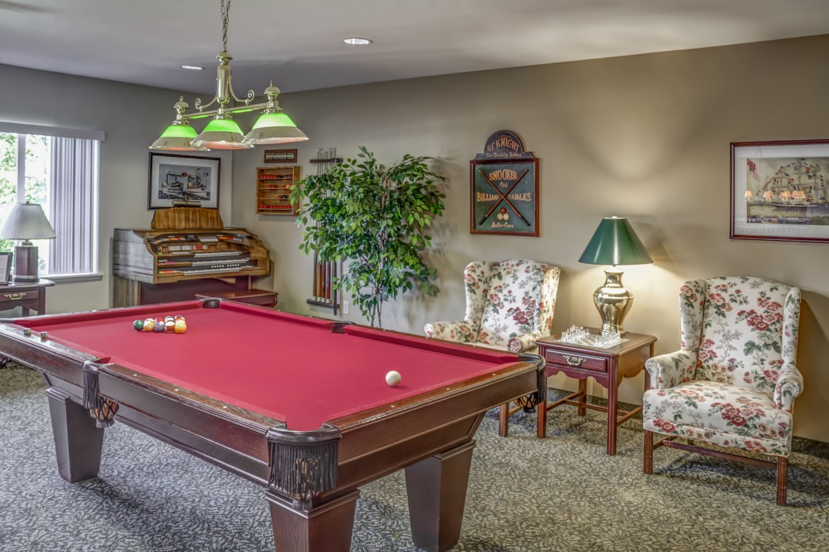 A cozy recreation room featuring a red pool table and comfortable seating.