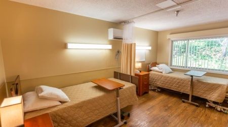 A hospital room with two patient beds separated by a curtain.