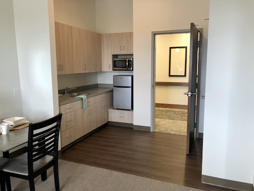 A modern kitchen in an apartment featuring wooden flooring and stainless steel appliances.