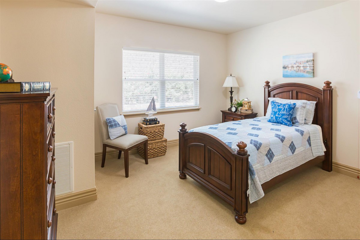 A cozy bedroom featuring a single bed, a window, and classic furnishings.