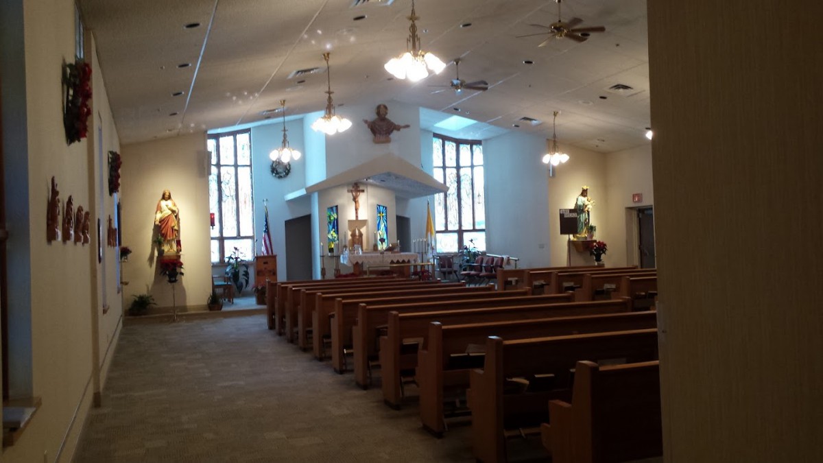Interior view of a church with wooden pews and stained glass windows.