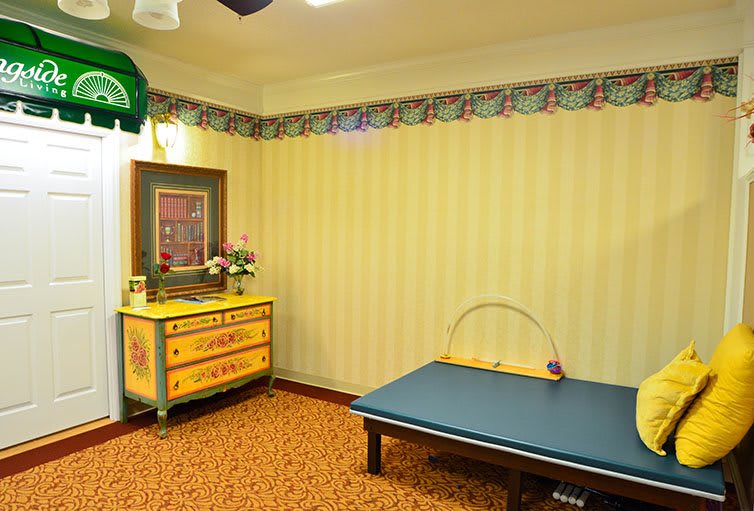 A cozy therapy room with a massage table and decorative furniture.